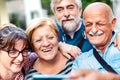 Happy senior friends taking selfie around old town street - Retired people having fun together with mobile phone