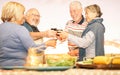 Happy senior friends toasting with red wine at barbecue dinner in terrace - Mature people dining and cheering together Royalty Free Stock Photo