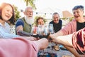 Happy senior friends toasting with red wine glasses at dinner on patio - Mature people having fun dining together outside