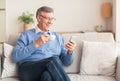 Happy Senior Gentleman Using Smartphone Having Coffee Sitting On Sofa Royalty Free Stock Photo