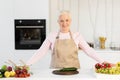 Happy Senior Lady Cooking In Kitchen Making Salad At Home