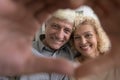 Happy senior loving couple portrait with hand heart shaped frame Royalty Free Stock Photo