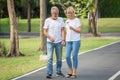 Happy senior loving couple relaxing at park walking with flower together in morning time. old people holding hand and enjoying Royalty Free Stock Photo