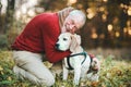 A senior man with a dog in an autumn nature at sunset.