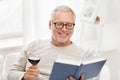 Happy senior man drinking wine and reading book Royalty Free Stock Photo