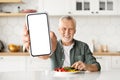 Happy Senior Man Eating Breakfast And Showing Big Blank Smartphone At Camera Royalty Free Stock Photo