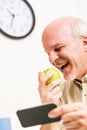 Happy senior man eating and using phone at work Royalty Free Stock Photo