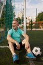 Happy senior man feeling tired after football training on soccer field Royalty Free Stock Photo