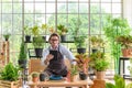 Senior man gardening wearing glasses and denim apron with digital tablet sitting in home gardening Royalty Free Stock Photo