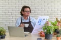 Happy senior man gardening wearing glasses and denim apron sitting and drinking coffee while reading newspaper in his home Royalty Free Stock Photo