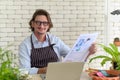 Happy senior man gardening wearing glasses and denim apron sitting and drinking coffee while reading newspaper in his home garden Royalty Free Stock Photo