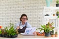 Happy senior man gardening wearing glasses and denim apron sitting and drinking coffee while reading newspaper in his home Royalty Free Stock Photo