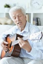 Happy senior man with guitar sitting on the sofa at home Royalty Free Stock Photo
