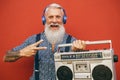 Happy senior man listening to music with wireless headphones and vintage boombox Royalty Free Stock Photo