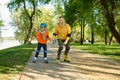 Happy senior man and little boy rollerskating in urban park Royalty Free Stock Photo