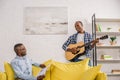 happy senior man with newspaper and smiling adult son with guitar looking at each other Royalty Free Stock Photo