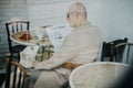 Happy senior man sitting in cafeteria with his dog and reading newspaper. Royalty Free Stock Photo