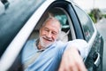 Happy senior man sitting in car in driver seat.