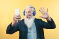 Happy senior man taking selfie while listening music with headphones - Hipster beard male having fun using mobile smartphone