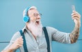 Happy senior man taking selfie while listening music with headphones - Hipster mature male having fun using mobile smartphone Royalty Free Stock Photo