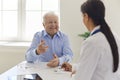 Happy senior patient talking to doctor in hospital office, thanking her for quick recovery Royalty Free Stock Photo