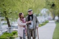 Happy senior man with walking stick and adult daughter outdoors on a walk in park. Royalty Free Stock Photo