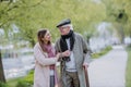 Happy senior man with walking stick and adult daughter outdoors on a walk in park. Royalty Free Stock Photo