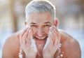 Happy senior man washing his face with snow, developing resistance to cold at frosty winter park Royalty Free Stock Photo