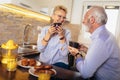 Senior man and woman couple sitting together at home smiling and drinking tea or coffee Royalty Free Stock Photo