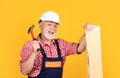 happy senior man woodworker in helmet on yellow background