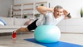 Happy senior man doing exercises with fitness ball at home, working out his back muscles, training with sports equipment Royalty Free Stock Photo