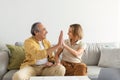 Happy senior couple giving high five using laptop and smiling at each other, sitting on couch at home, copy space Royalty Free Stock Photo