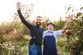 A senior man and adult son standing arm in arm in apple orchard in autumn. Royalty Free Stock Photo