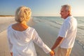 Happy Senior Old Retired Couple Walking Holding Hands on Beach at Sunset Royalty Free Stock Photo