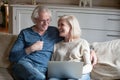 Happy senior couple laughing relaxing with laptop in living room Royalty Free Stock Photo