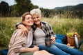 Happy senior mother embracing adult daughter when sitting and having picnic outdoors in nature. Royalty Free Stock Photo