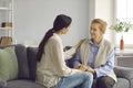 Happy senior mother and young daughter sitting on couch, holding hands and talking Royalty Free Stock Photo