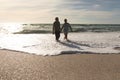 Happy senior multiracial couple enjoying retirement in waves on shore at beach against sky Royalty Free Stock Photo