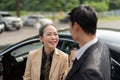 Happy senior old asian businesswoman discussion talking about new project with young asian male colleague at car park. Royalty Free Stock Photo