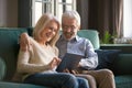 Happy senior old couple sit on sofa using digital tablet Royalty Free Stock Photo