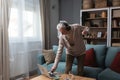 Happy senior old grandfather man in wireless headphones dancing, singing at home, choosing favorite energetic disco music in Royalty Free Stock Photo