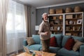 Happy senior old grandfather man in wireless headphones dancing, singing at home, choosing favorite energetic disco music in Royalty Free Stock Photo