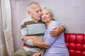 Happy affectionate mature old man and woman embracing looking at camera