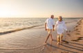 Happy Senior Old Retired Couple Walking Holding Hands on Beach at Sunset Royalty Free Stock Photo