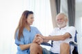 Happy senior patient in wheelchair with beautiful female nurse taking care of him at home, disabled elderly man sits in wheelchair Royalty Free Stock Photo