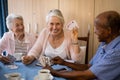 Happy senior people playing cards while having coffee