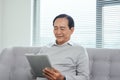 Happy senior relaxing at home and using tablet
