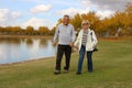 Happy Senior Retired Couple Walking by a Lake at the Park