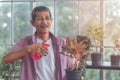 Happy Senior retired man spraying water on plant pot welness hobby lifestyle