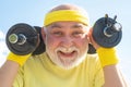 Happy Senior sport man exercising with lifting dumbbell on blue sky background. Isolated, copy space. Royalty Free Stock Photo